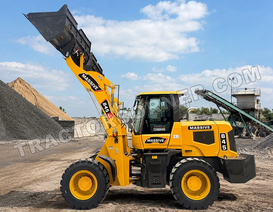 Yellow front-end loader with raised bucket at a quarry, gravel piles in the background.